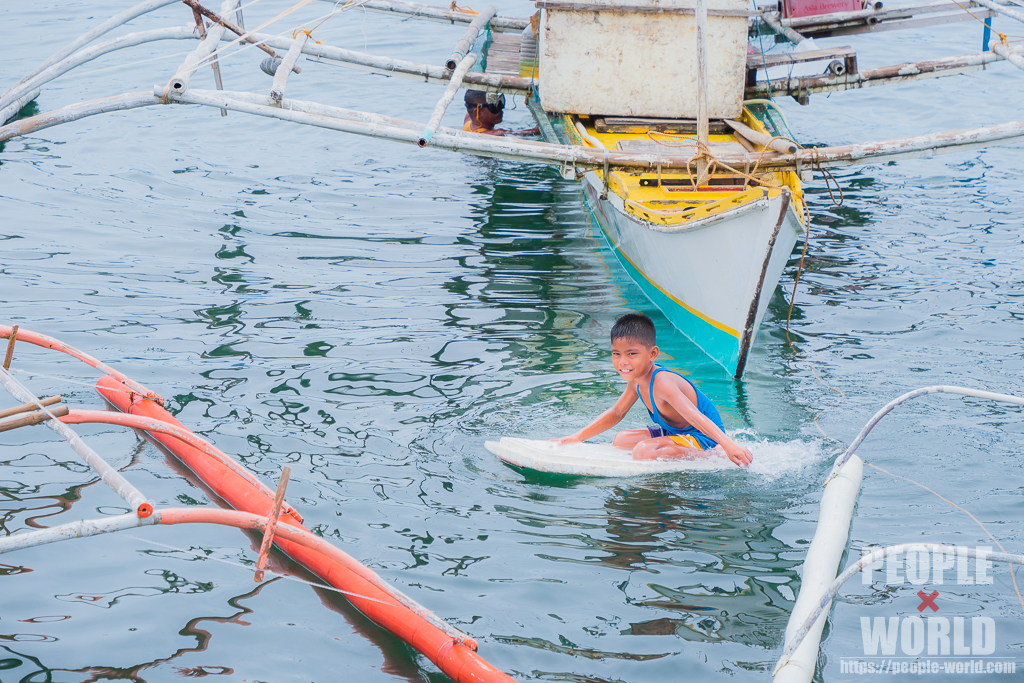 手作りのサーフボードで遊ぶ子供（フィリピン）