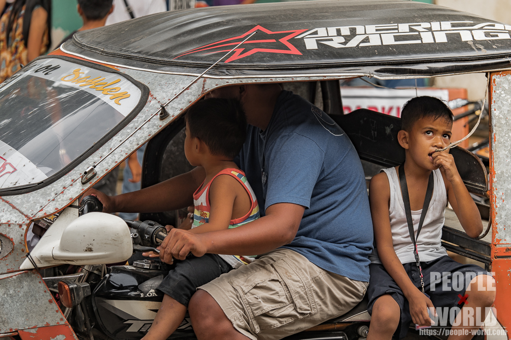 トライシクルドライバーの膝の上に座る子供（フィリピン）
